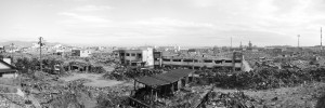 《石巻市定点撮影 2011/2015 No.3 高台から南浜町4丁目方面を望む(南方向)。 津波により甚大な被害を受けた門脇町、南浜町。海岸の防波堤を越えて約7mの津波が一帯に押し寄せた。ほとんどの住宅や建物は水没し、津波に押し流された自動車から火災が発生し、一昼夜燃え続けた。現在では被災した建物の撤去が進み、一部の区域では区画整理のための造成が始められている。(Ishinomaki City Then and now: Four Years after the Tohoku Earthquake, #3 Overlooking Minamihamacho 4 chome from the hilltop. (Viewing south) Kadonowakicho and Minamihamacho were seriously destroyed by Tsunami. The two towns were struck by 7 meter high Tsunami against which the breakwater along the shore was helpless. Most of the houses and buildings in the town sunk under the water, while automobiles pushed away by Tsunami caused a fire. It kept burning though day and night. By now, rubbles have been removed and some parts of the town are under rezoning.)》2011/2015