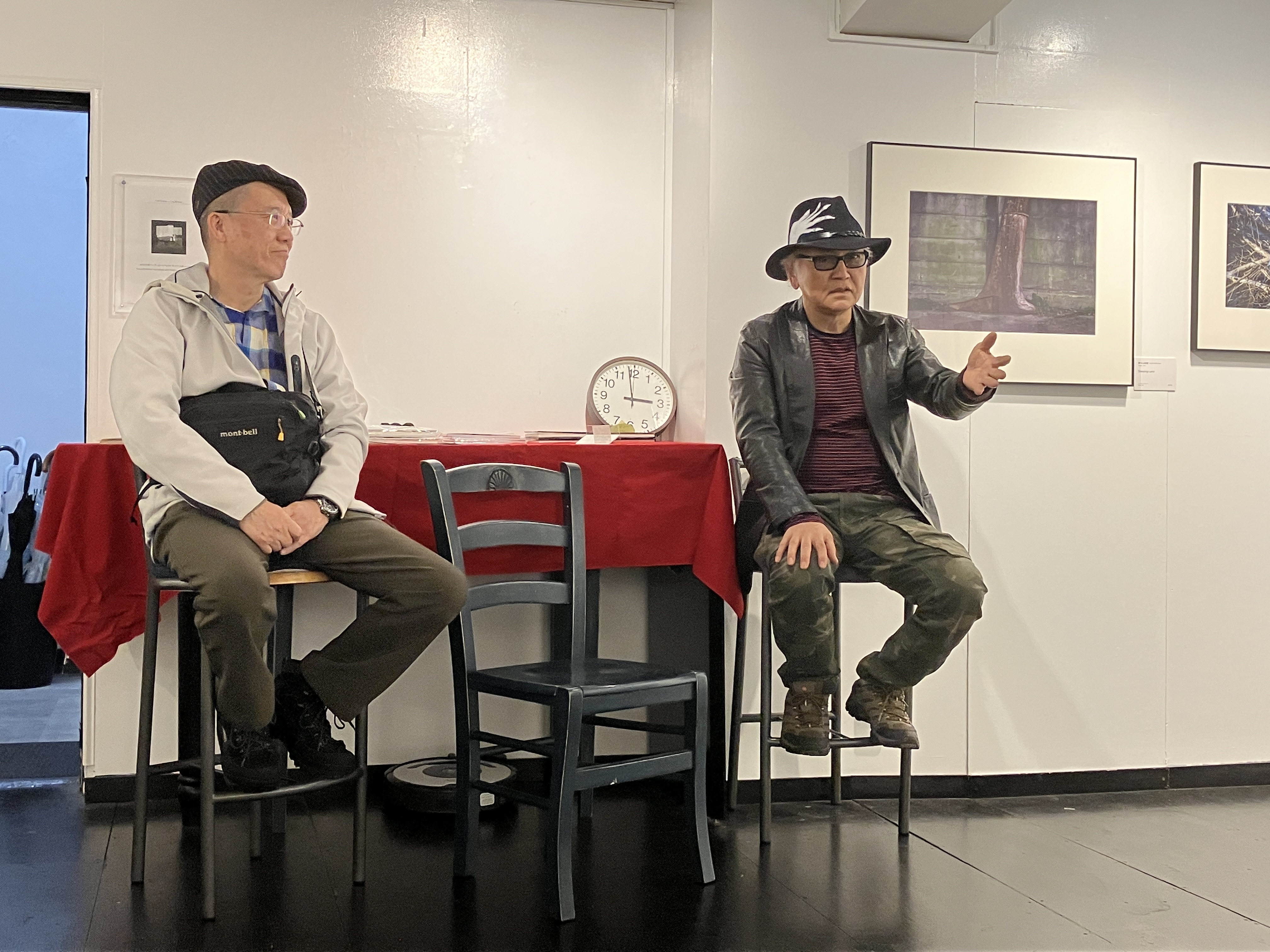 左：写真家・三好和義氏　右：瀬戸正人　脚の長い椅子に座っている。瀬戸が手のジェスチャーも交えながら聴衆に語りかけている様子。