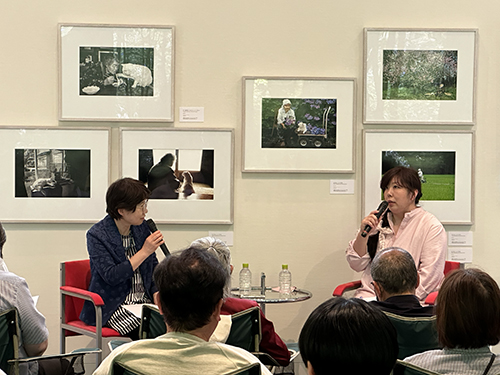 トーク・イベント中の伊原美代子さん(向かって右側。左側は当館職員)展示期間中のパトリにて開催。自身の作品を背に、撮影中のエピソードなどを語られた